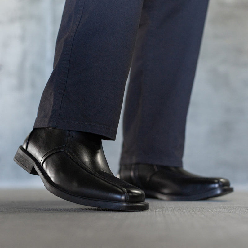 Black leather side-zip ankle boot with dark pants, side view