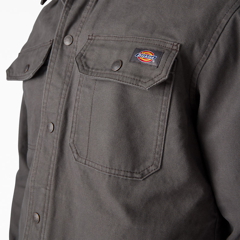Men's duck shirt jacket detail: flap chest pocket with logo patch, dark gray fabric.