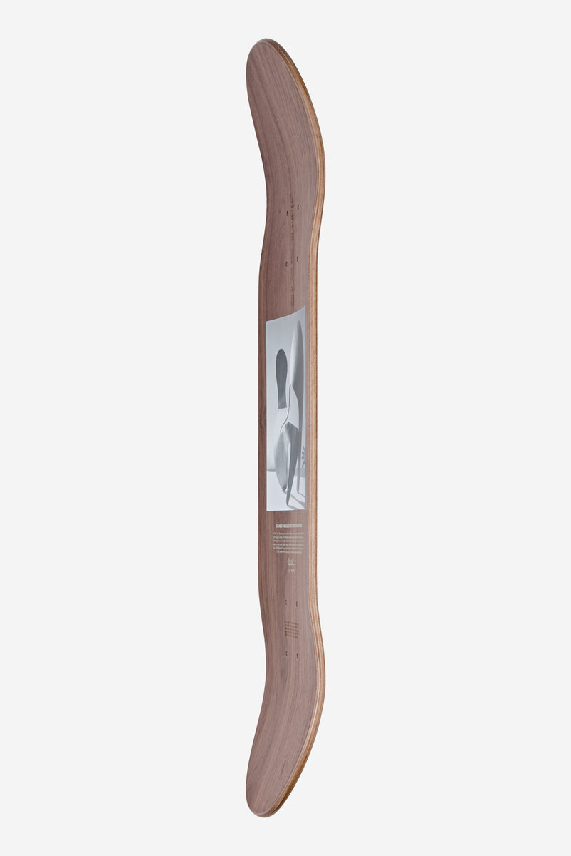 Side view of the Eames Silhouette 8.0 walnut plywood deck showing its curved profile and a grayscale art print on the face for wall display