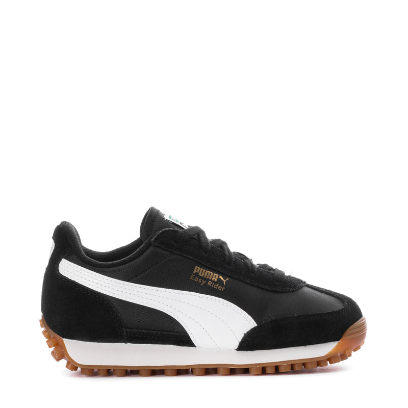 Kids Puma sneaker in black with white stripe and gum sole, side view.