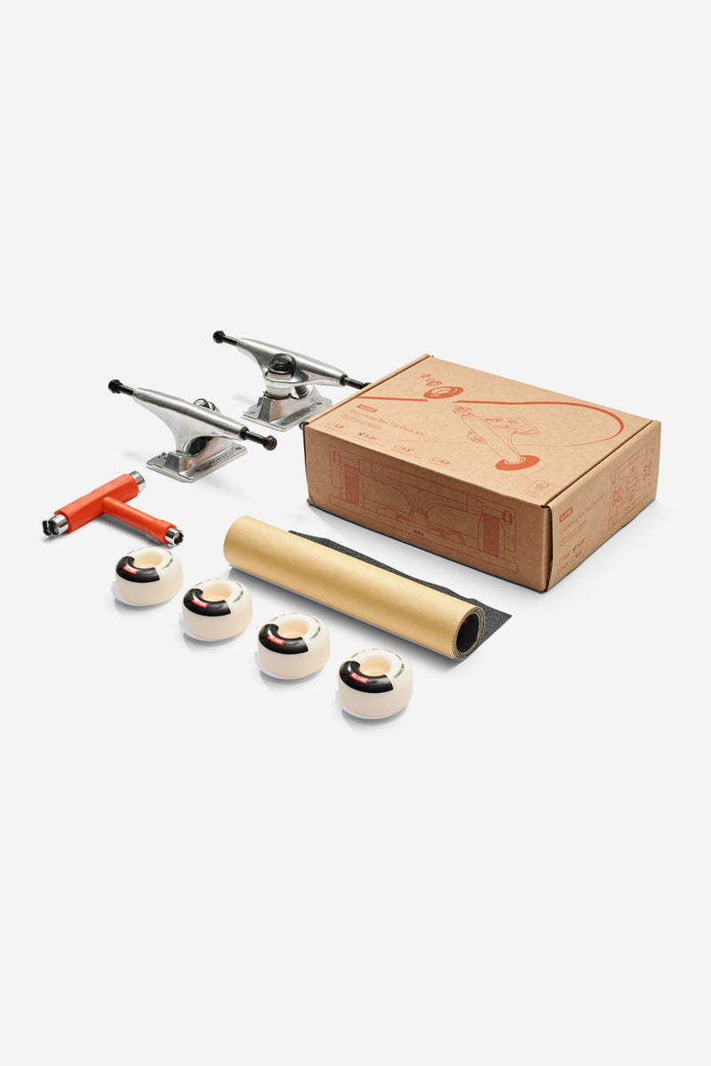 Everything But The Deck 5.0 kit components with a cardboard box, grip tape, two trucks, wheels, bearings, hardware and Globe decals