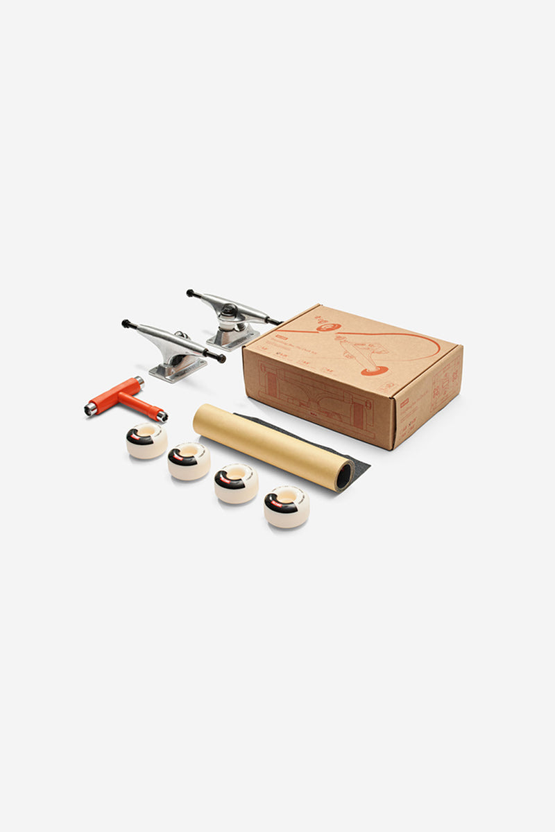 Skateboard kit contents with four wheels a red T-tool and grip tape beside the kit box