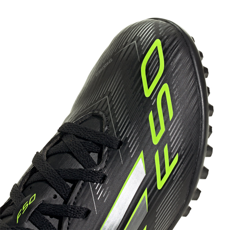 Youth black cleats close-up: neon green F50 logo on textured upper with laces