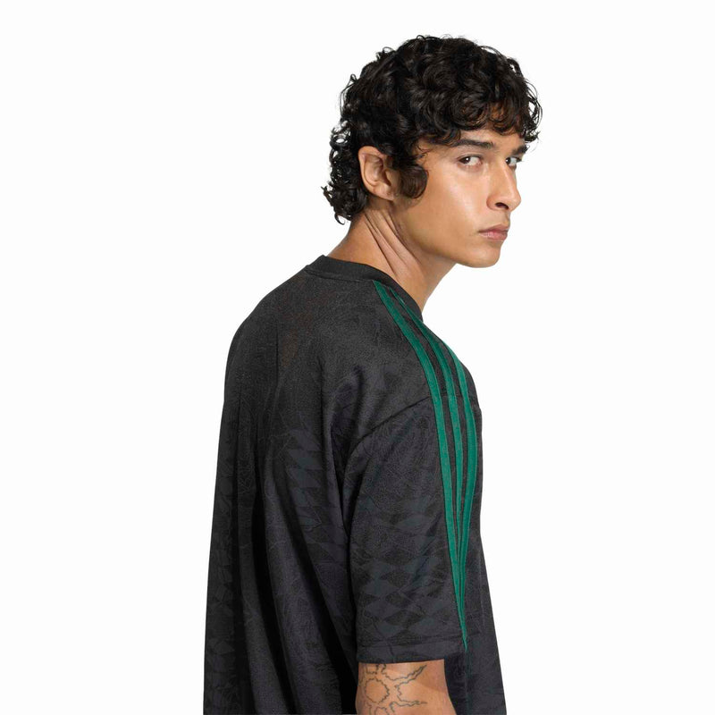 Men's black football jersey side view with green shoulder stripe and subtle pattern texture