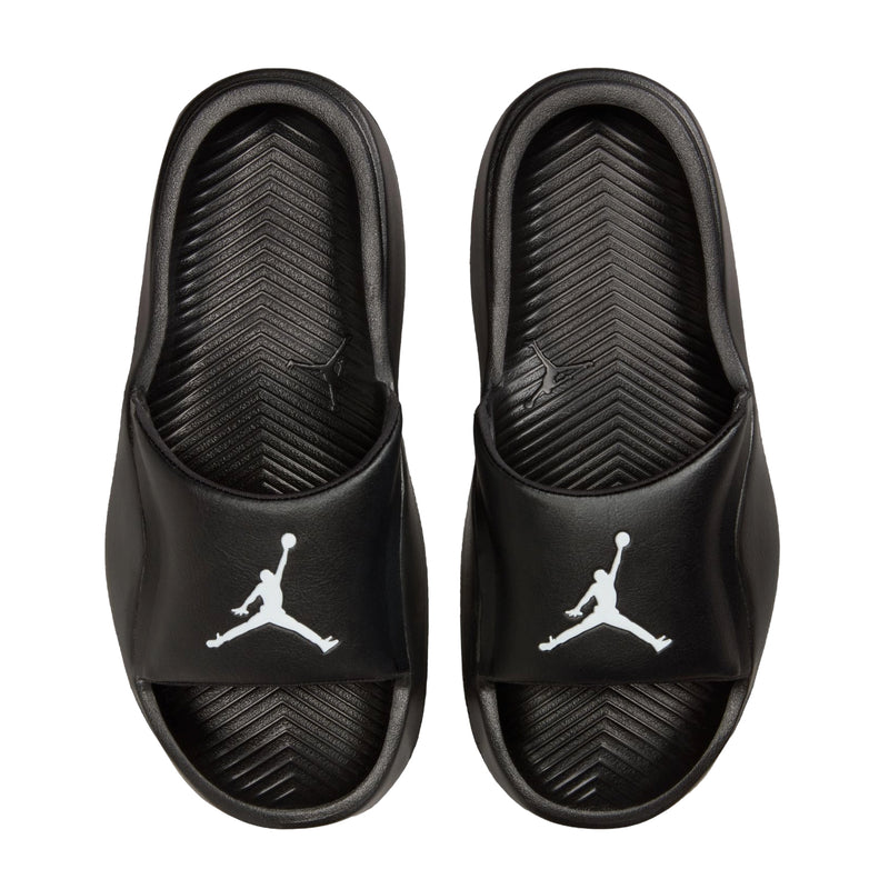 Black youth slide sandals with white Jordan logos on the footbed, top view.