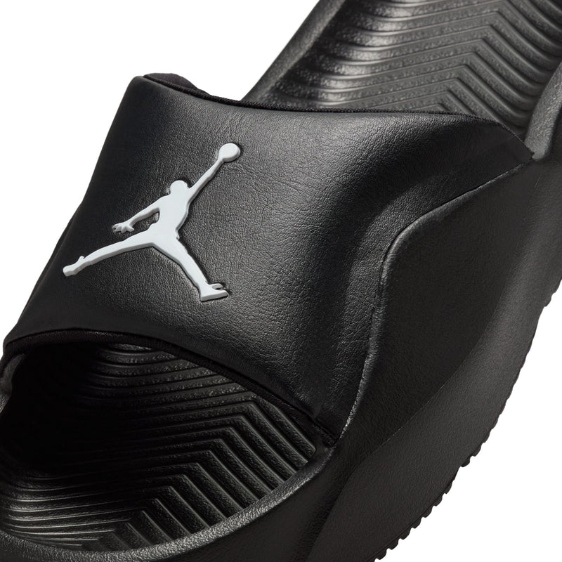 Black textured slide sandal upper with white Jordan logo detail, close-up.