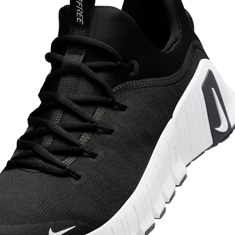 Close-up of men's black sneakers with laces, knit texture, and white logo panel