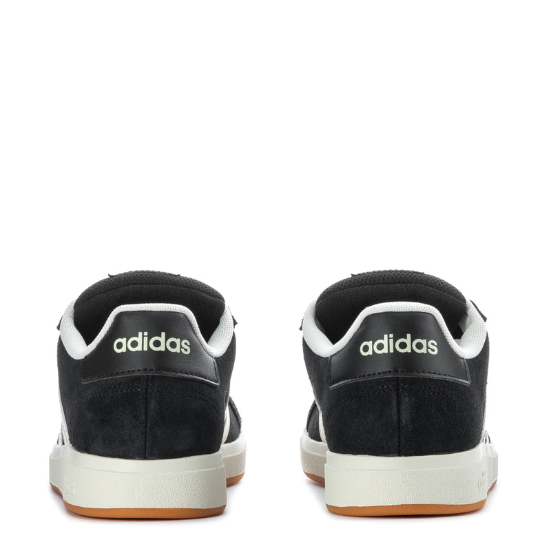 Youth Adidas sneakers in black with white stripes and gum outsole, heel view.