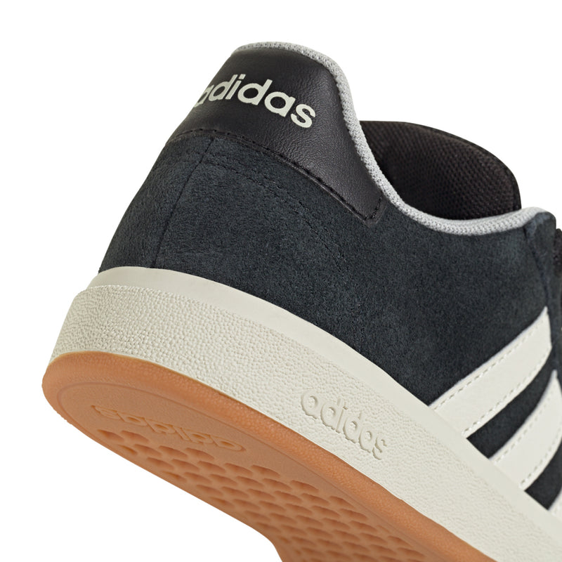 Black Adidas sneaker close-up at heel with white stripes and gum midsole.