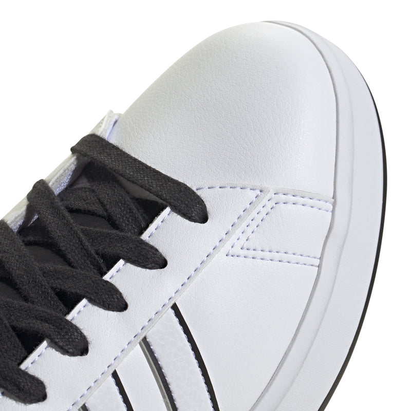 White sneaker upper close-up with black laces and black side three-stripe detail