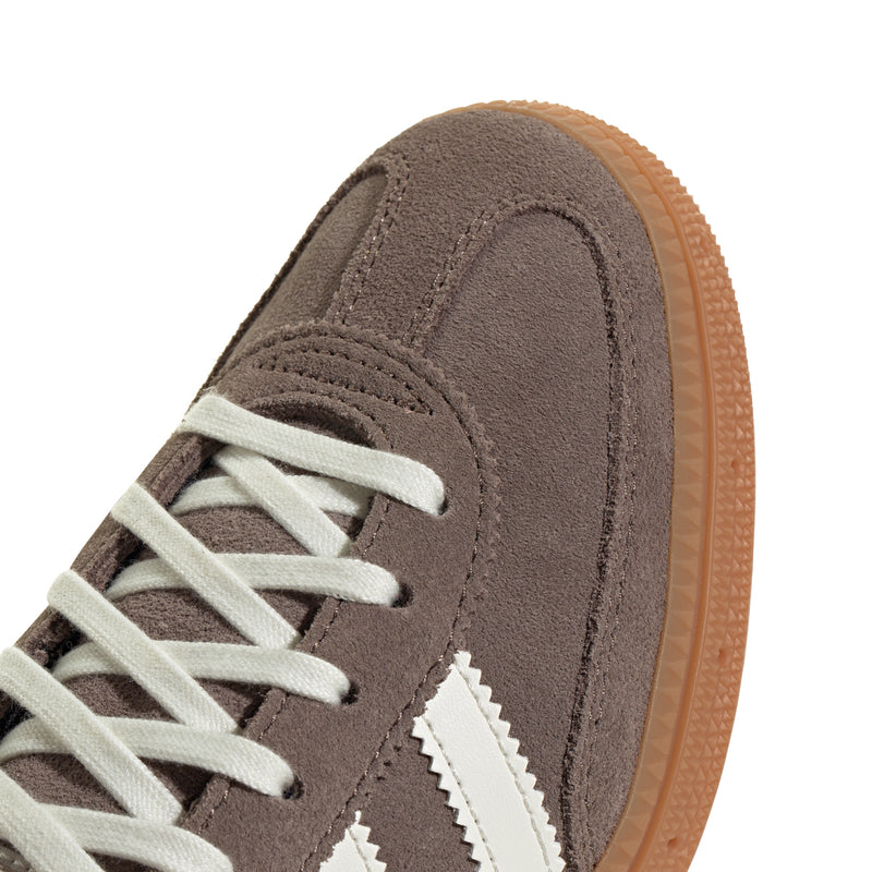 Youth sneaker toe panel close-up, brown suede with cream stripes and orange sole edge.