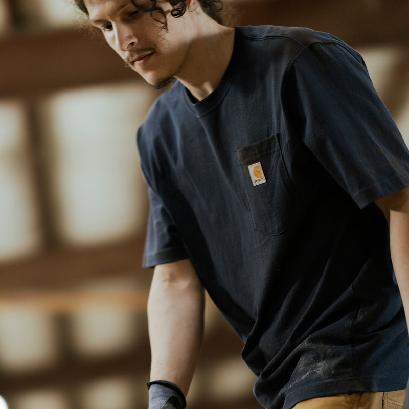 Men's navy loose-fit pocket T-shirt with front chest pocket and Carhartt label, side view