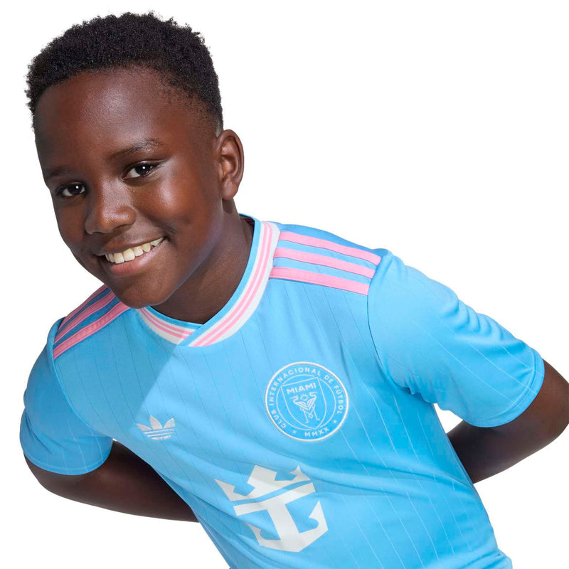 Youth light-blue soccer jersey close-up with pink striped collar and anchor emblem