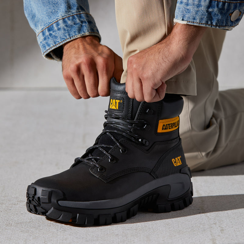Men's black steel-toe work boot with laces and yellow CAT logo, shown being tied