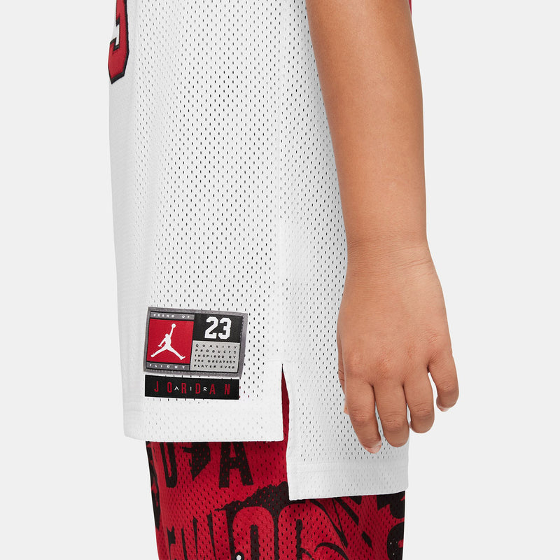White youth jersey side hem with small Jordan logo patch and red '23' accents