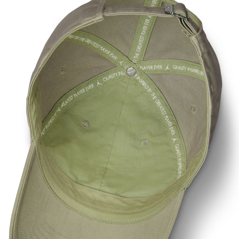 Khaki cap interior with adjustable strap and printed text on lining.