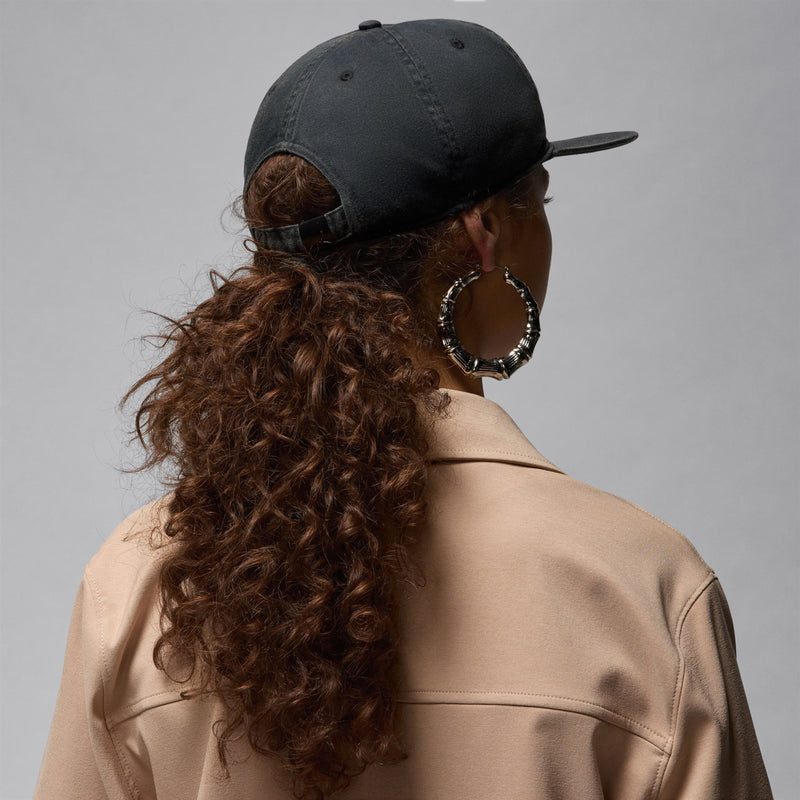 Dark 5-panel strapback cap, back view with adjustable strap detail