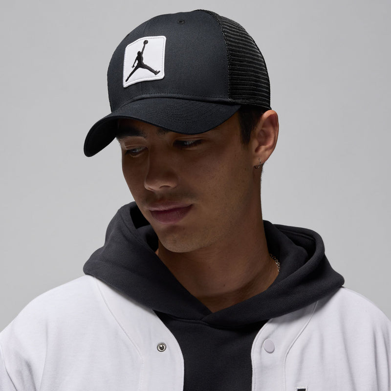 Black trucker cap with white Jumpman patch worn with a dark hoodie
