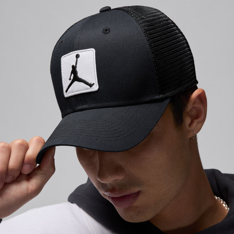 Black trucker cap, side view with white Jumpman patch and curved brim