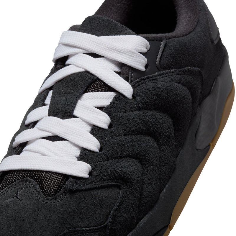 Close-up of black suede sneakers with white laces and molded side panel