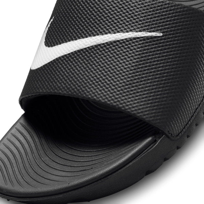 Kids black slide sandal close-up: white Nike swoosh on textured upper