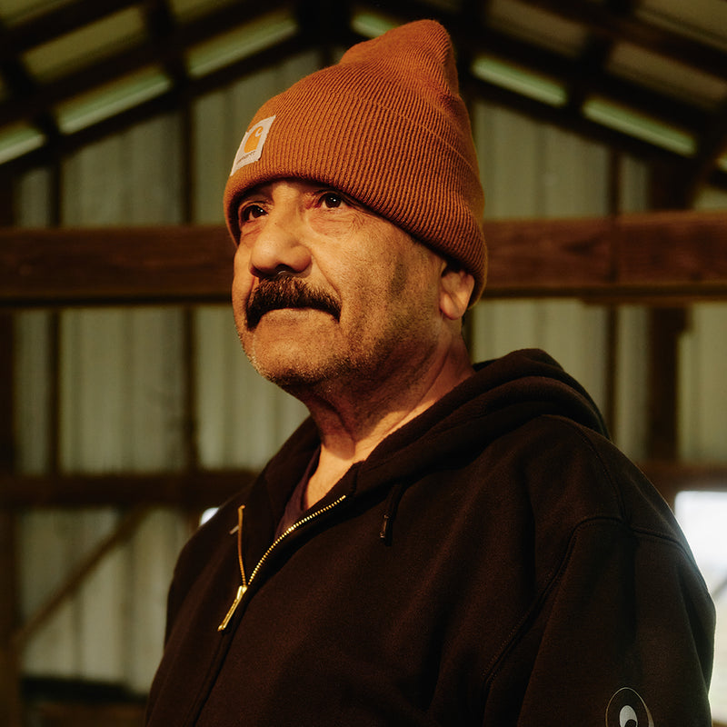 Carhartt brown knit beanie with front logo patch, worn to one side.