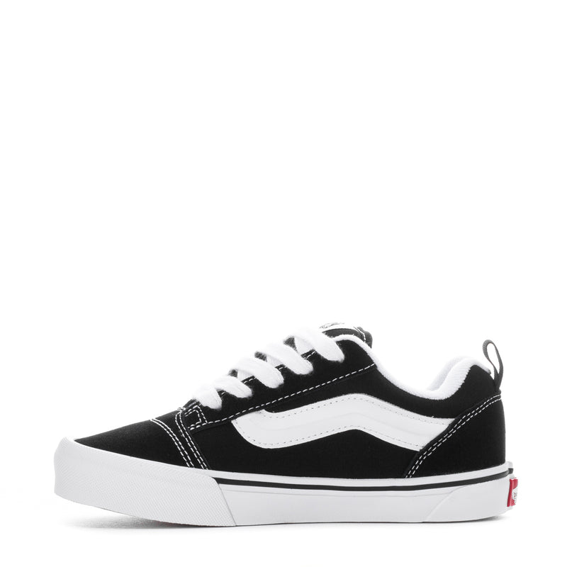 Kids black-and-white lace-up low-top skate shoes with white side stripe.