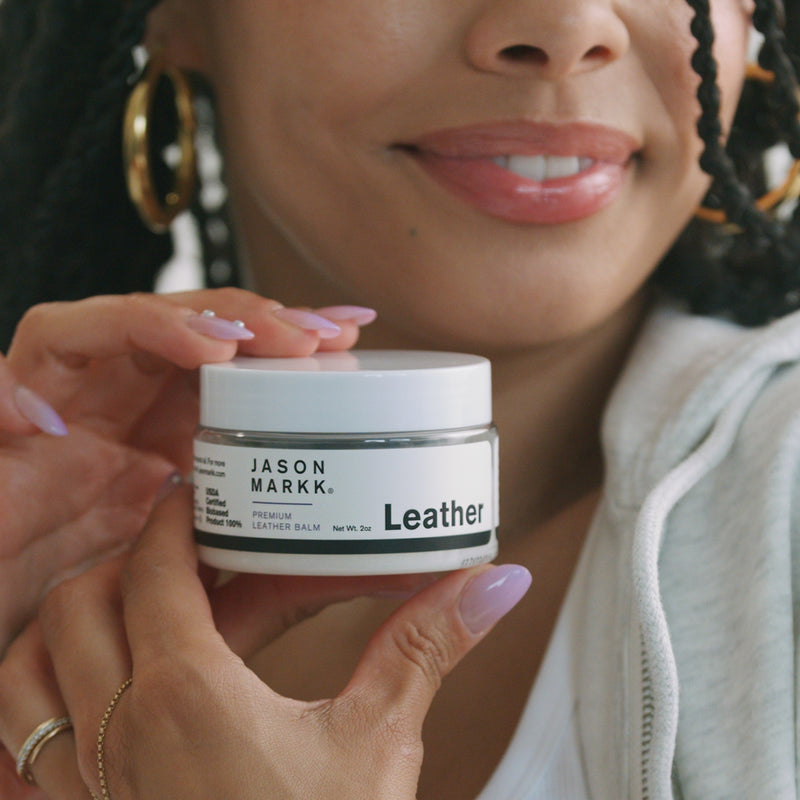 Leather conditioning balm jar held in hands, white jar with black JASON MARKK Leather label
