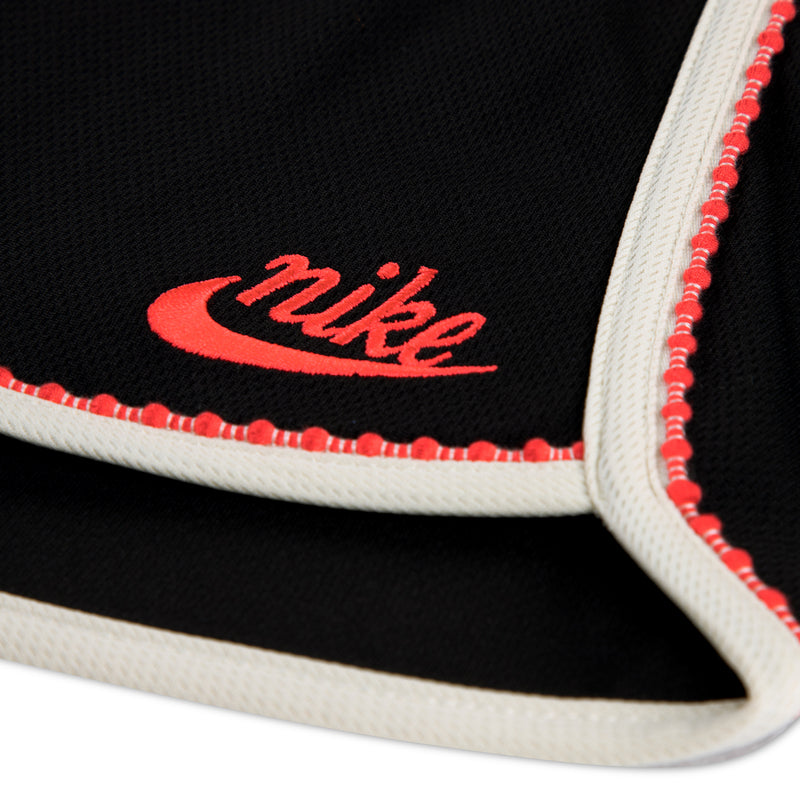 Black athletic shorts cuff detail with red Nike text and white trim