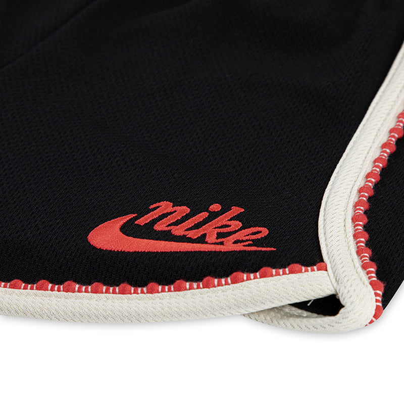 Black toddler shorts hem with Nike logo, red stitch trim and white edge