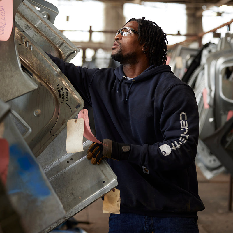Men's hoodie in dark navy teal, hood up; sleeve logo visible.