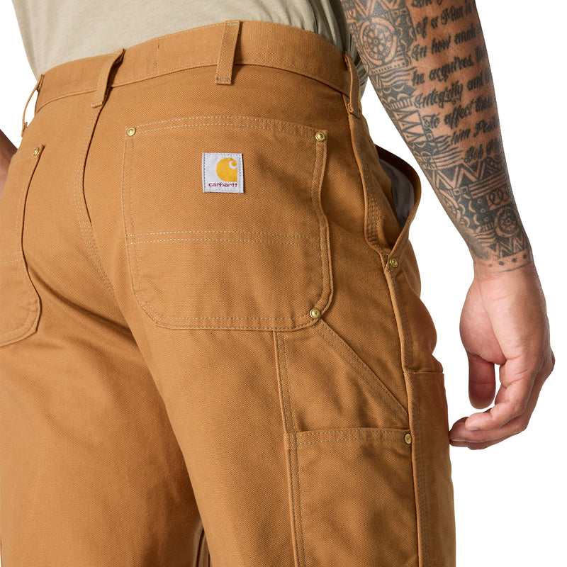 Brown dungaree pants close-up: back yoke, branded label, and double-stitch pockets