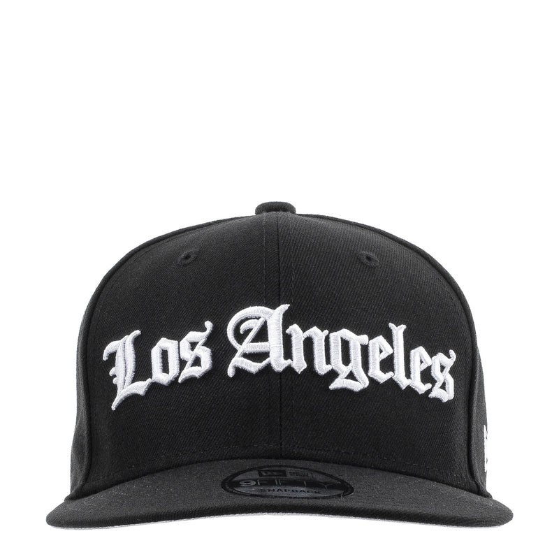 Black baseball cap with white Los Angeles script logo on the front panel