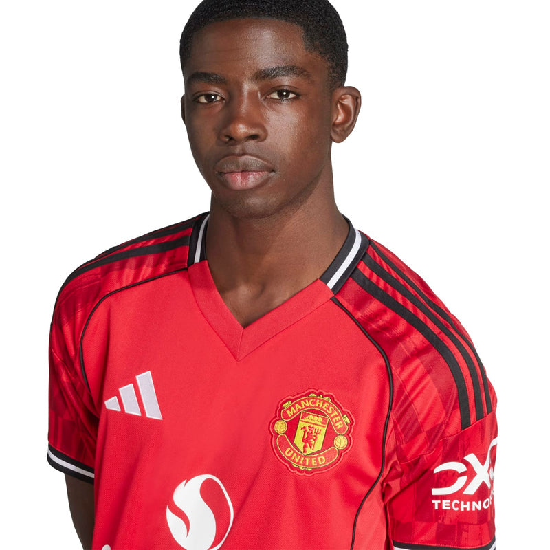Men's red jersey close-up with Manchester United crest, black shoulder stripes and V-neck