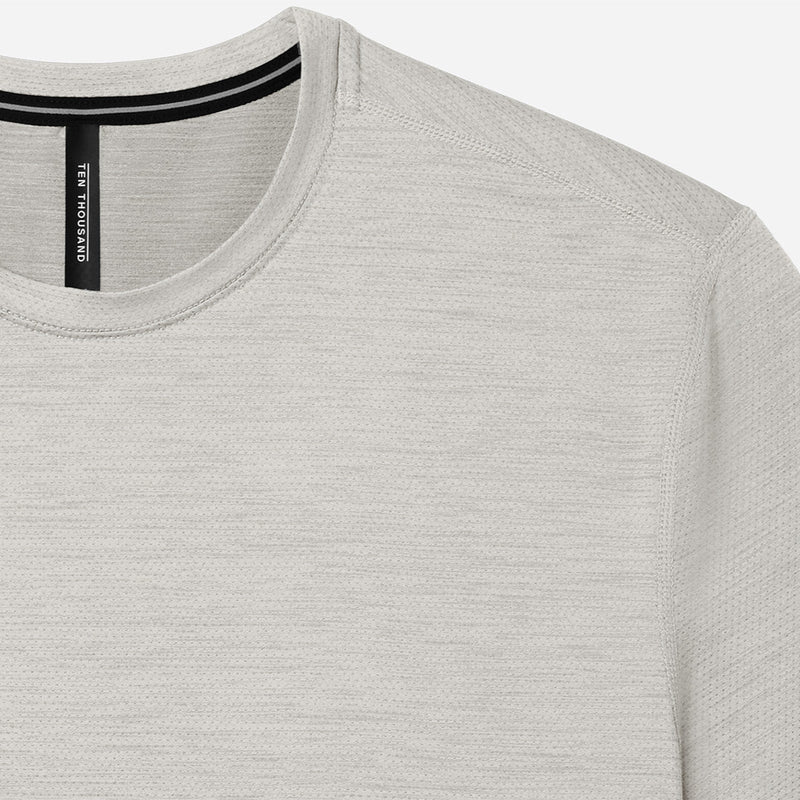 Close-up of a light gray t-shirt with a brand label on a white background