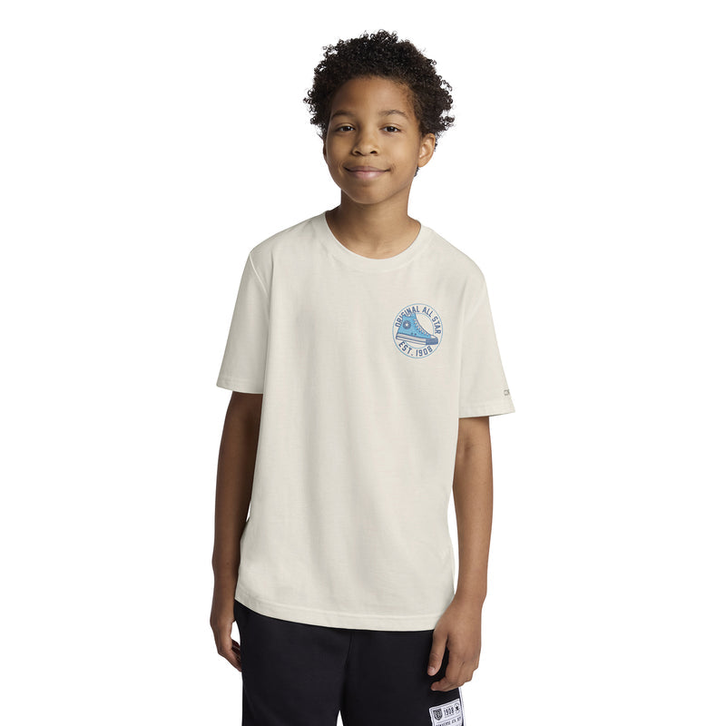 Youth off-white T-shirt worn by child, blue Converse chest graphic and short sleeves