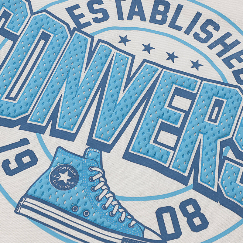 Close-up graphic detail: blue Converse lettering and sneaker print on off-white tee