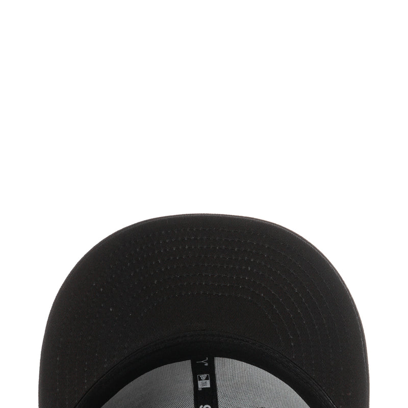 Black cap brim close-up with textured fabric and stitched interior seam