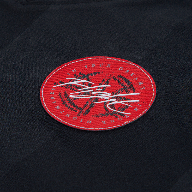 Black jersey patch with red circular logo and white script embroidery