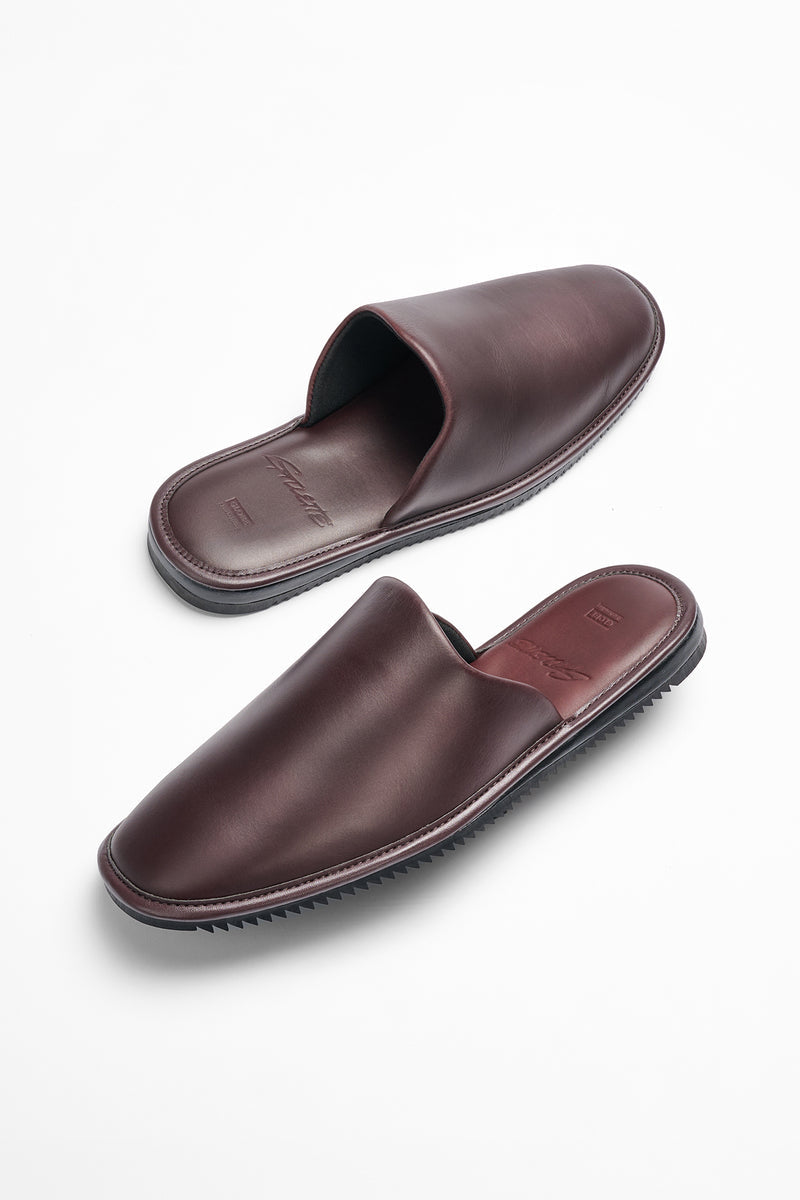 Oxblood leather mule with a minimalist silhouette, stitched edges, and a black Vibram Mini Ripple sole.