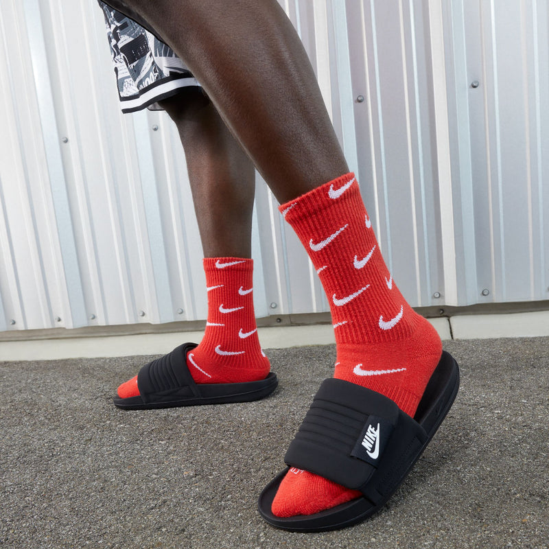 Red-and-black slide sandals with black strap, worn with red socks