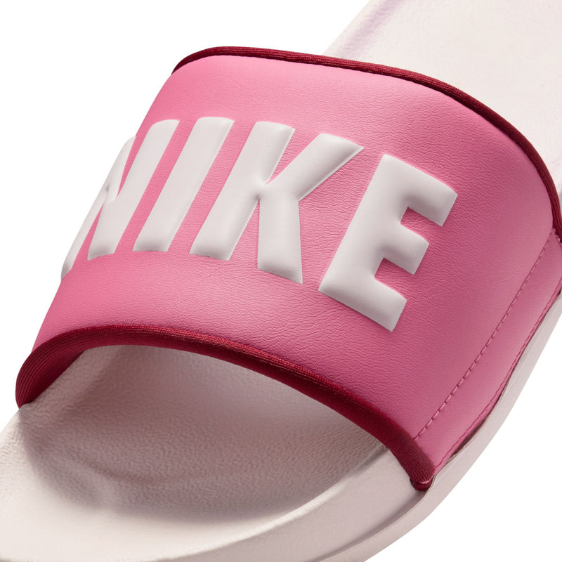 Women's slide sandal close-up, pink textured strap with large white NIKE letters