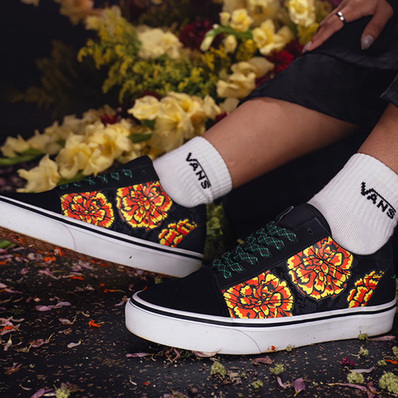 Black low-top sneakers with marigold floral print straps and green laces