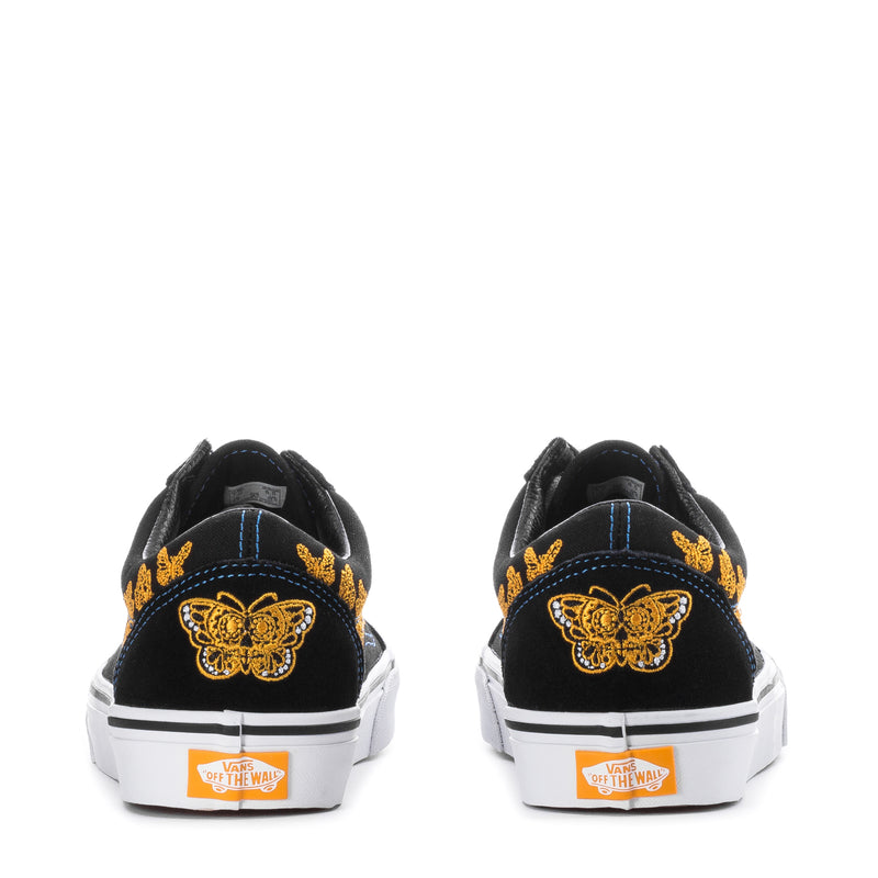 Women's sneakers back view, black with yellow butterfly embroidery, white rubber heel
