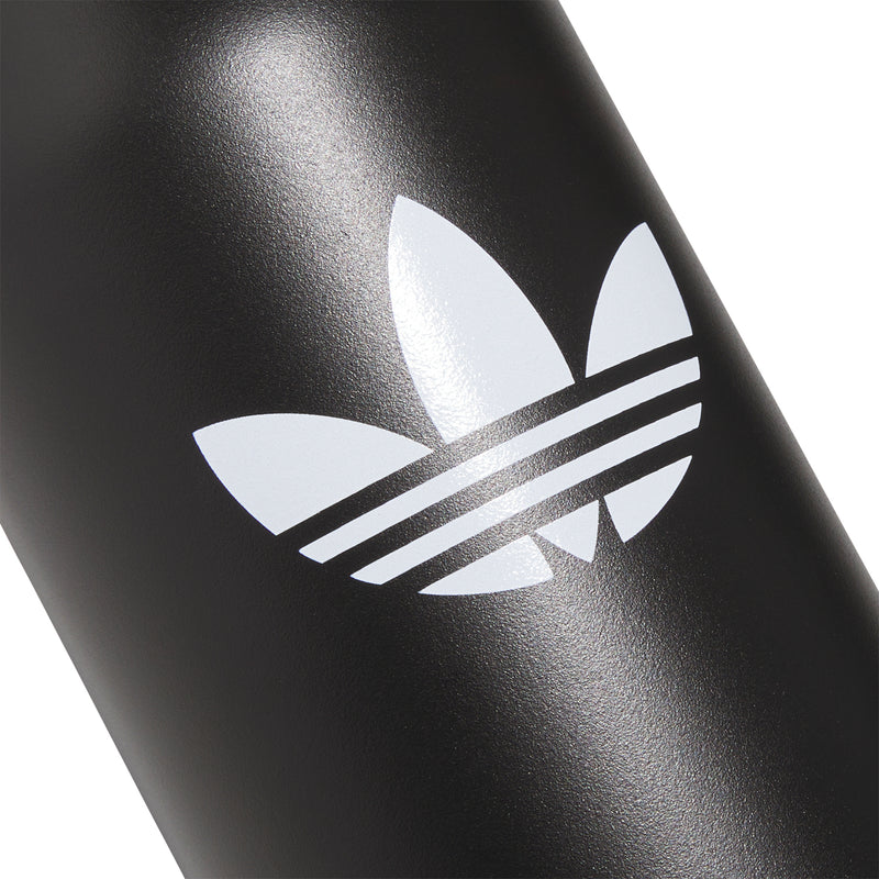 Matte black bottle with large white trefoil and stripes logo, close-up