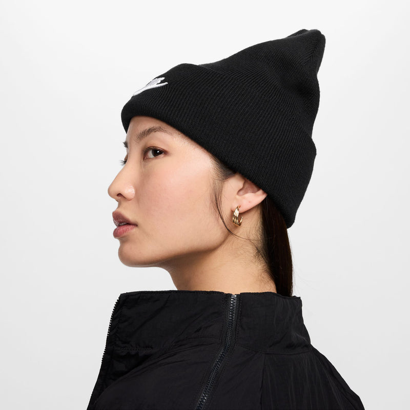 Black Nike beanie with white swoosh logo, side profile view on a model.