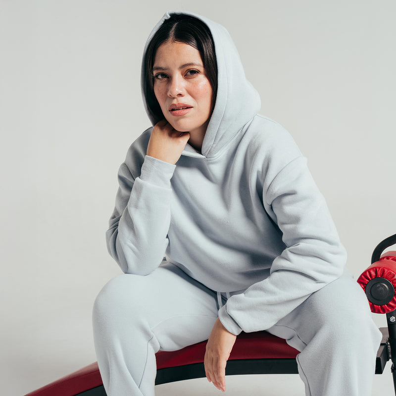 Light blue-gray fleece hoodie with hood and kangaroo pocket, seated wear