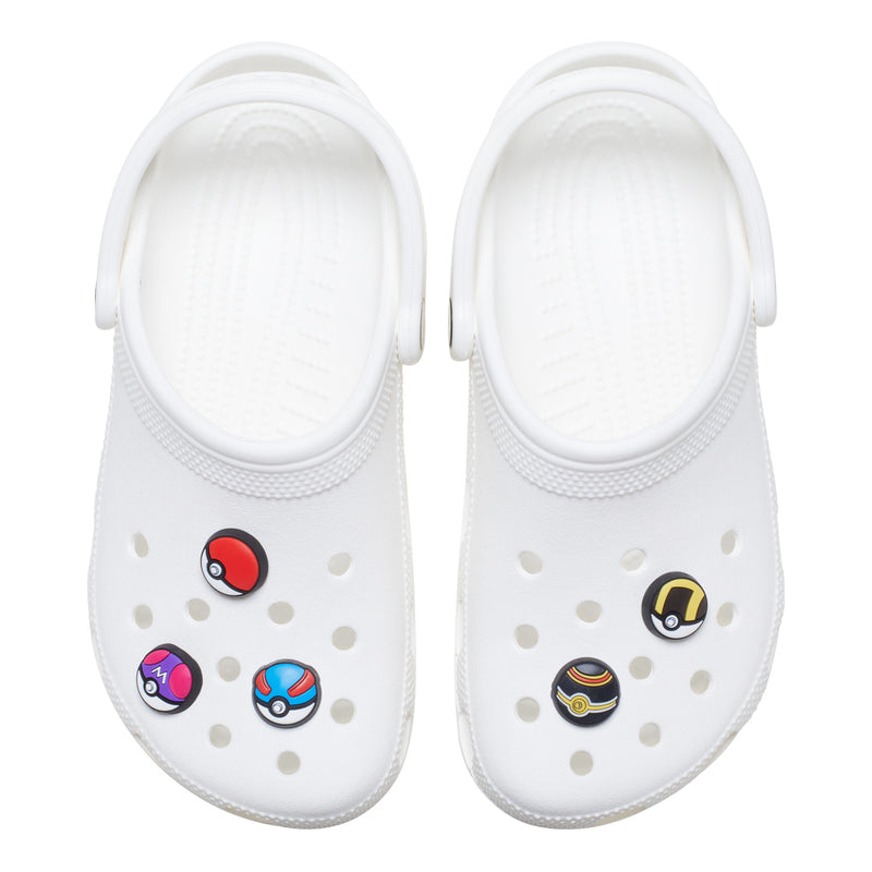 White clogs with pokeball-style Jibbitz charms, multicolor enamel