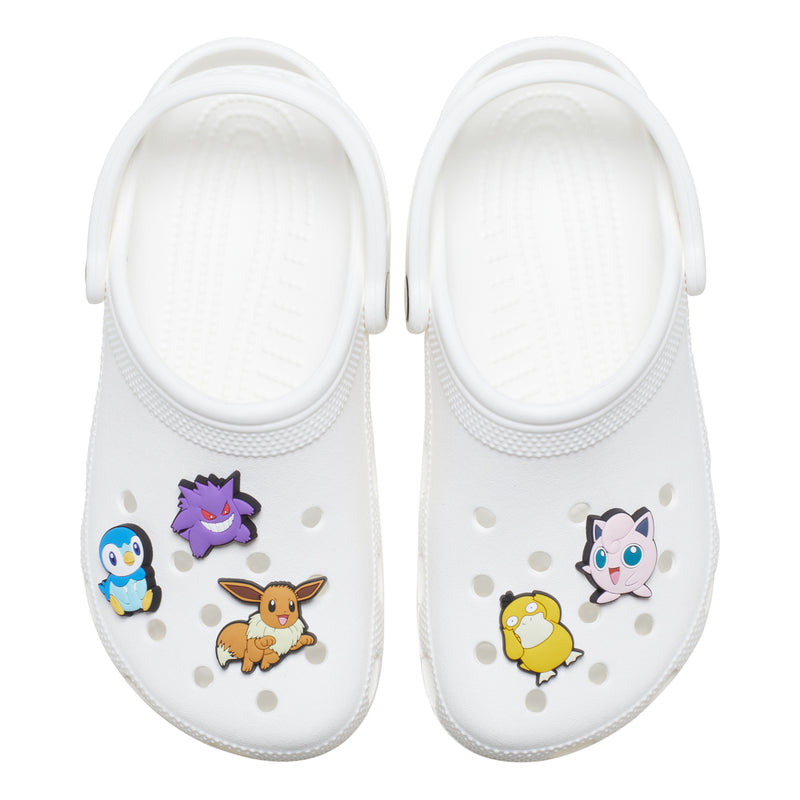 White clogs with five Pokemon Jibbitz charms, including penguin and purple fox