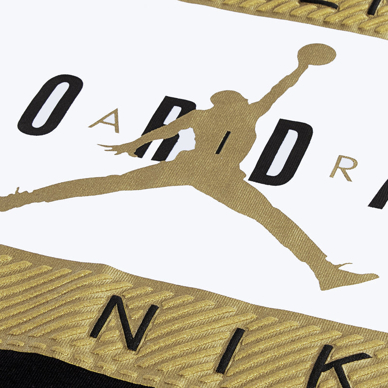 Close-up of gold-and-black Jumpman graphic on youth tee label